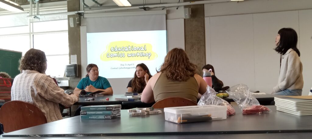 Instructor welcomes students, seated at table with art supplies, with title slide projected in background.